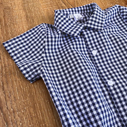 Collared blue and white checkered shirt on a wooden surface with white buttons