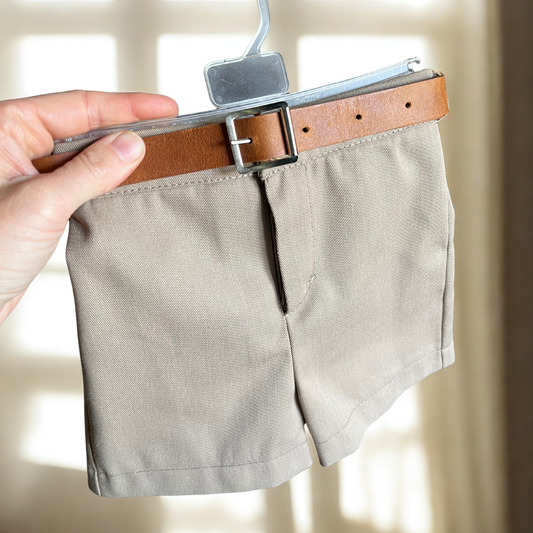 Beige baby shorts on a hanger with a brown belt