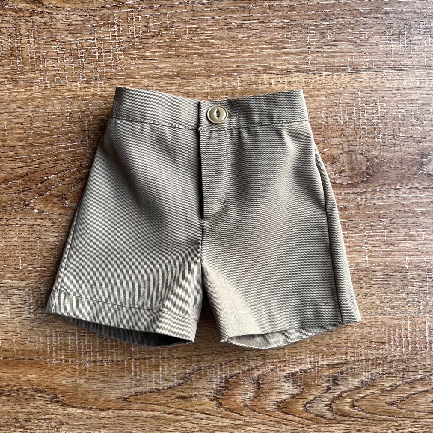 Tan baby boy chino shorts shorts on a wooden surface