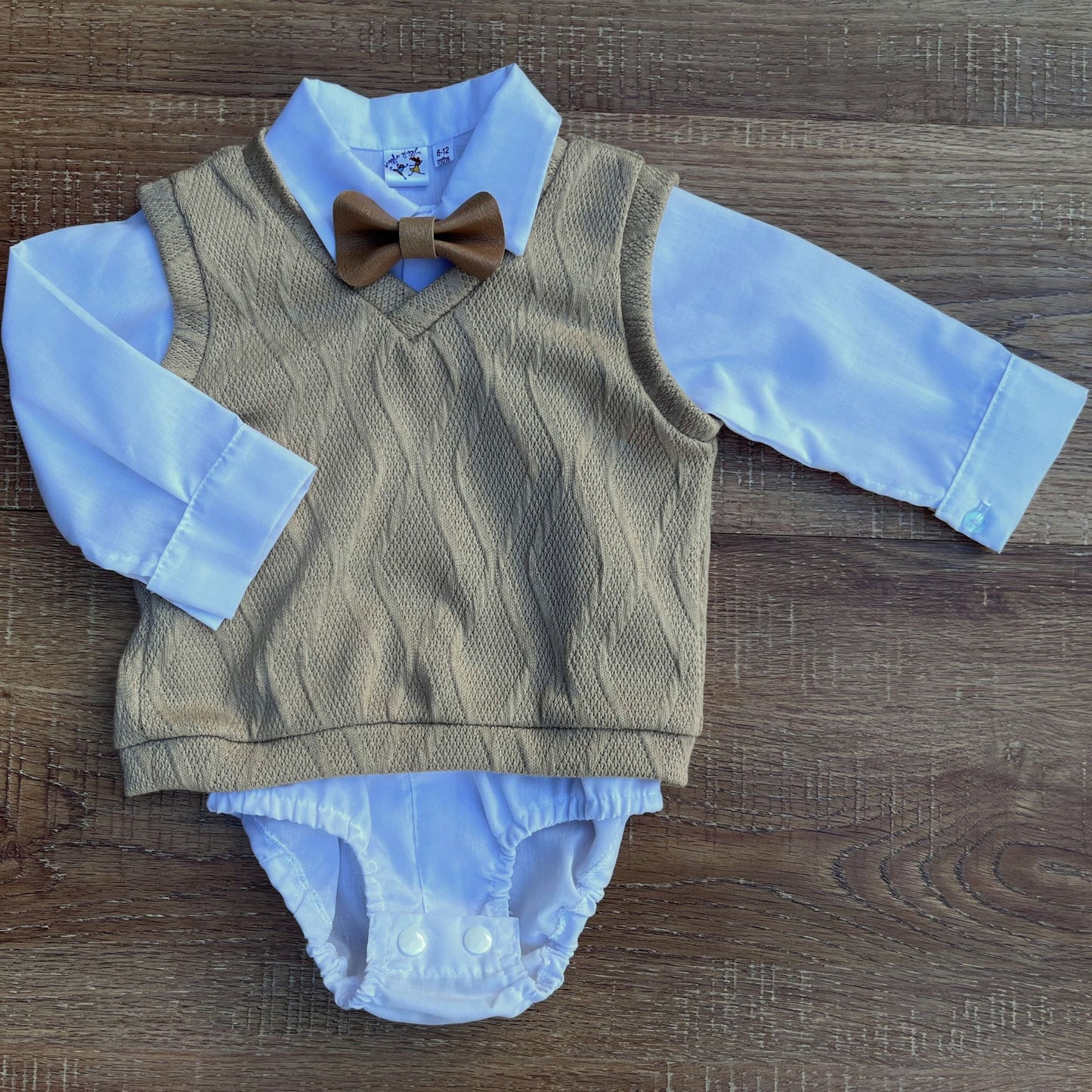 Baby boy outfit with brown cardigan, white shirt on a wooden surface