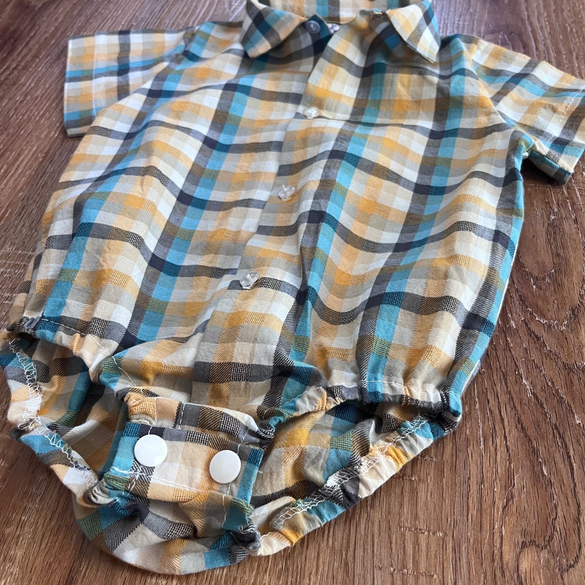 Check baby boy romper shirt on a wooden surface