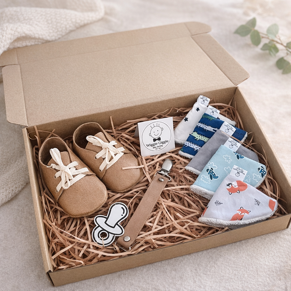 Baby gift set with baby leather shoes, leather pacifier clip and pee pee teepee's in a box on a soft surface.
